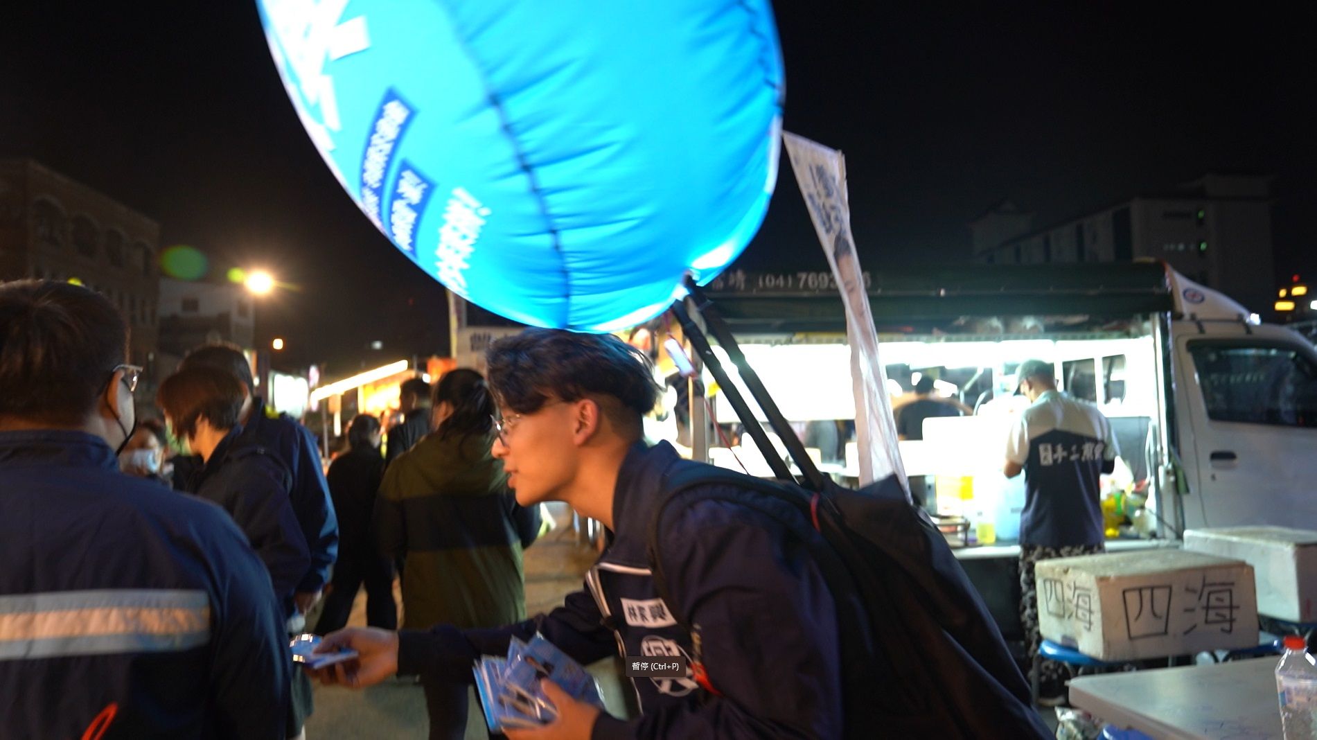 23歲葉承瑄背著充氣燈牌在夜市發候選人的宣傳面紙。